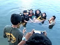 川から引き上げた水死体を前に記念撮影をするダイビングチームの映像が話題に。